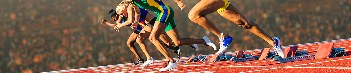 Four female athletes on athletics track, leaving starting blocks